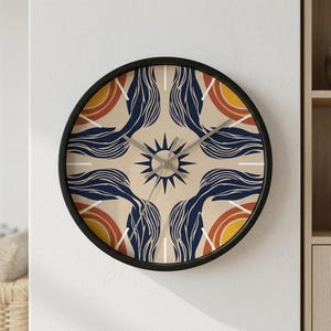 May include: Round wall clock with a black frame. The clock face features a beige background with a symmetrical design of navy blue, orange, and yellow shapes, and a central sunburst. The clock hands are silver.