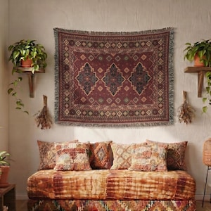 May include: A rectangular woven wall tapestry featuring a deep burgundy background with a central pattern of three dark blue diamond-shaped medallions surrounded by intricate geometric borders and small floral motifs, finished with a fringed edge.