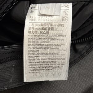 Peut inclure: Gros plan sur un tissu noir avec une &eacute;tiquette blanche attach&eacute;e. L'&eacute;tiquette contient du texte en plusieurs langues, dont le japonais et l'anglais, d&eacute;taillant la composition du tissu, avec des pourcentages de polyester et d'autres mat&eacute;riaux.