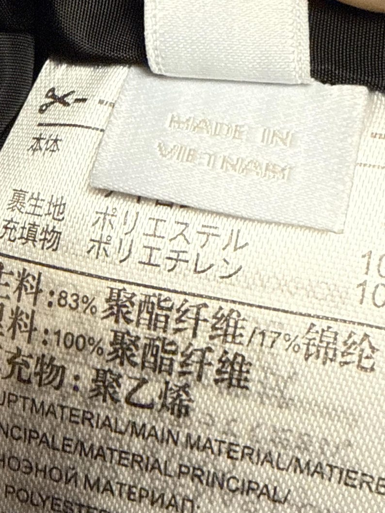 Peut inclure: Gros plan sur une &eacute;tiquette blanche avec du texte en plusieurs langues. L'&eacute;tiquette indique "MADE IN VIETNAM" et d&eacute;taille les mat&eacute;riaux, dont le polyester et le poly&eacute;thyl&egrave;ne.