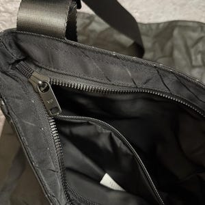 Peut inclure: Sac bandouli&egrave;re noir avec un motif textur&eacute; et un compartiment principal zipp&eacute;. Le sac est dot&eacute; d'une bandouli&egrave;re noire r&eacute;glable et d'une petite poche zipp&eacute;e &agrave; l'int&eacute;rieur. L'int&eacute;rieur est noir.