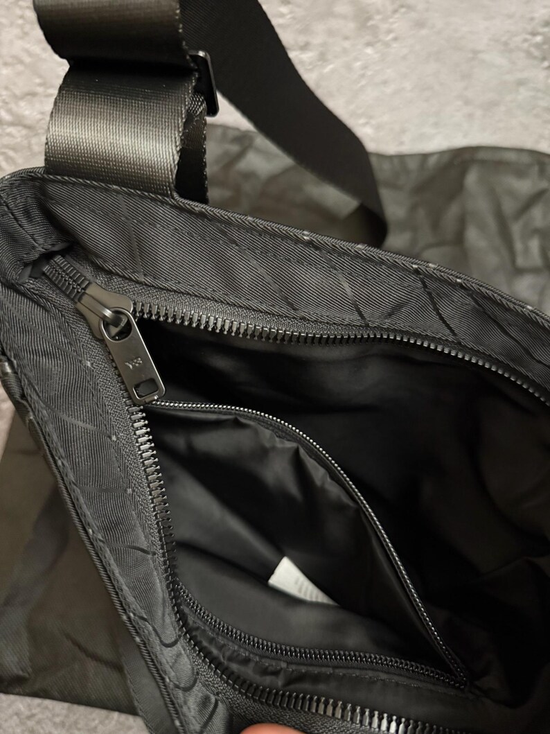 Peut inclure: Sac bandouli&egrave;re noir avec un motif textur&eacute; et un compartiment principal zipp&eacute;. Le sac est dot&eacute; d'une bandouli&egrave;re noire r&eacute;glable et d'une petite poche zipp&eacute;e &agrave; l'int&eacute;rieur. L'int&eacute;rieur est noir.