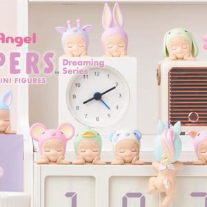 May include: A collection of Sonny Angel Hippers decorative mini figures from the Dreaming Series. The figures are in various animal and fantasy-themed costumes, including a giraffe, bunny, and lion. The figures are displayed on a white shelf with a clock and a vintage radio.