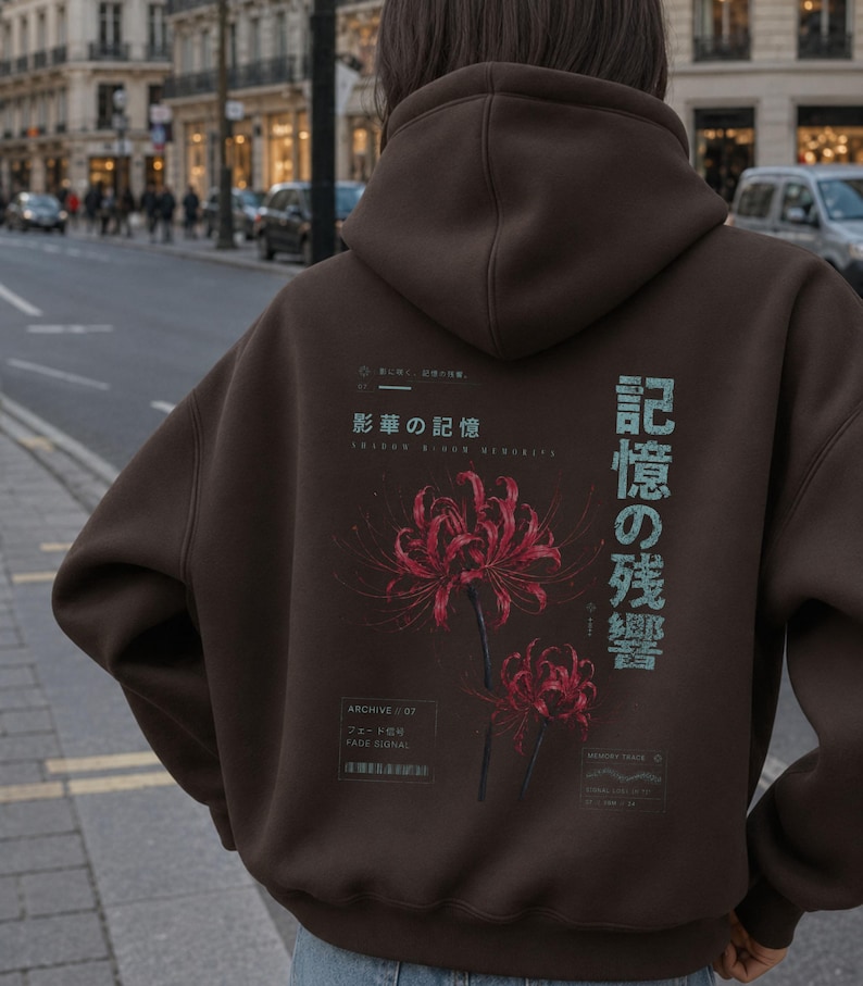 May include: A dark brown hooded sweatshirt featuring a graphic print on the back. The design includes two red spider lily flowers, Japanese text, and smaller English text elements including "ARCHIVE 07" and "FADE SIGNAL" in a technical layout.