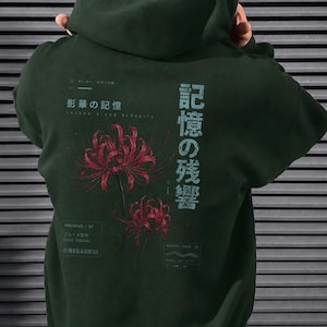 May include: A dark forest green hooded sweatshirt featuring a graphic on the back. The design includes two red spider lily flowers, Japanese text, and smaller English text elements including "Archive // 07", "Fade Signal", and "Memory Trace".