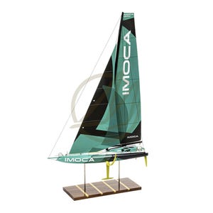 Peut inclure: Maquette de voilier avec une voile turquoise et noire, avec le texte "IMOCA" en blanc. Le bateau a une base en bois et des accents jaunes. C'est un objet décoratif.