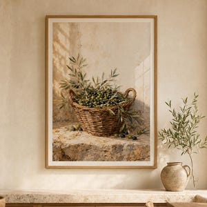 Può includere: Una stampa artistica incorniciata raffigurante un cesto di vimini intrecciato pieno di olive verdi fresche e rami frondosi, appoggiato su una superficie in pietra strutturata contro una parete beige neutra, catturando una scena mediterranea rustica.