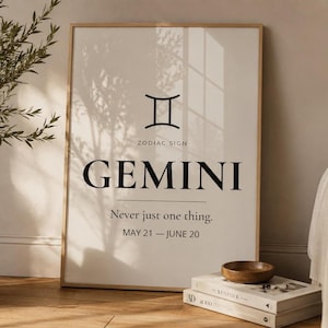 Può includere: Una stampa incorniciata con il simbolo zodiacale dei Gemelli e la parola "GEMINI" in nero. Il testo "Never just one thing. MAY 21 - JUNE 20" è presente. Una ciotola di legno è appoggiata su una pila di libri.