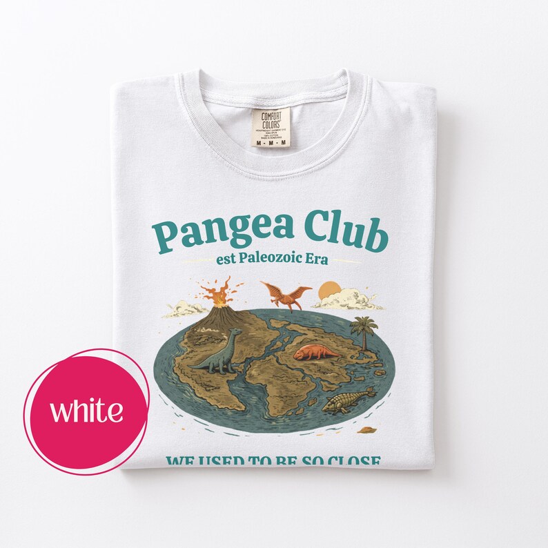 Peut inclure: T-shirt blanc avec un motif graphique. Le motif pr&eacute;sente les mots "Pangea Club" et "est Paleozoic Era", une carte de la Terre avec des dinosaures, un volcan et le texte "WE USED TO BE SO CLOSE."