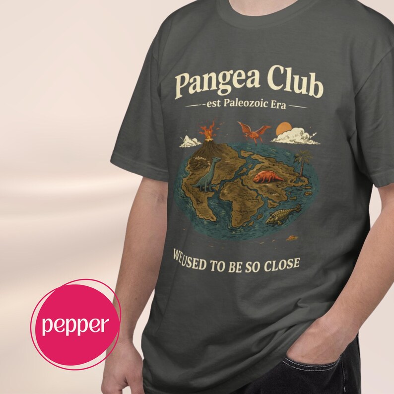 Peut inclure: T-shirt gris fonc&eacute; avec l'inscription "Pangea Club - est Paleozoic Era". Le t-shirt pr&eacute;sente un dessin de la Terre avec des dinosaures et le texte "WE USED TO BE SO CLOSE."