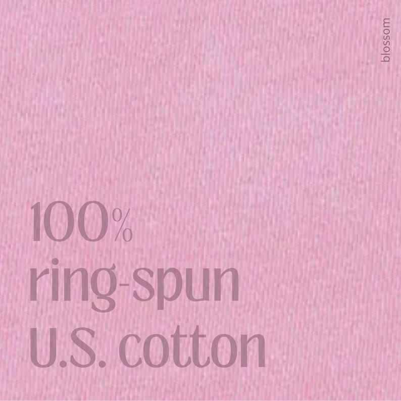 May include: A close-up of a pink fabric with the text "100% ring-spun U.S. cotton" in a darker pink font. The word "blossom" is printed vertically in the upper right corner.