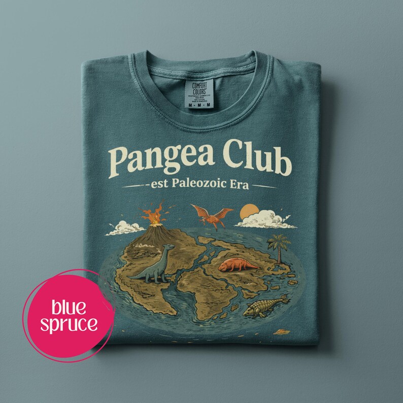 Peut inclure: T-shirt bleu &eacute;pic&eacute;a avec le texte "Pangea Club - est Paleozoic Era" et un dessin de dinosaures, d'un volcan et d'un soleil au-dessus d'une masse terrestre. Le t-shirt est pli&eacute; et porte une &eacute;tiquette Comfort Colors.