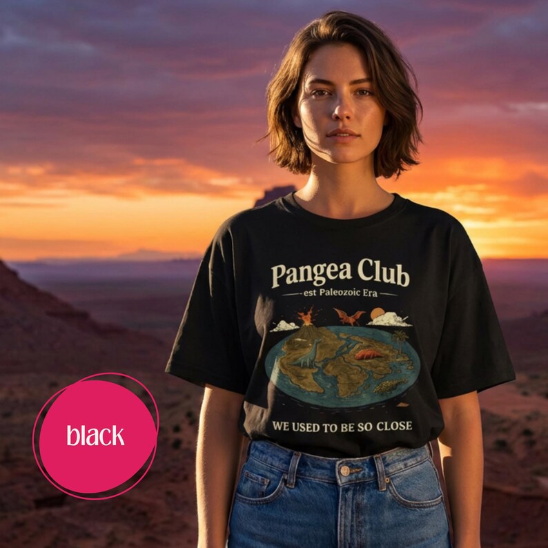 Peut inclure: T-shirt noir avec l'inscription "Pangea Club - est Paleozoic Era" et un dessin du supercontinent de la Pang&eacute;e. Le t-shirt porte &eacute;galement l'inscription "WE USED TO BE SO CLOSE". Le mod&egrave;le porte un jean bleu.