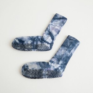 May include: A pair of tie-dye socks in shades of blue and white. The socks have a non-slip grip on the soles. The socks are made of a soft, comfortable material.