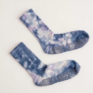 May include: A pair of tie-dye socks in shades of blue, purple, and white. The socks have a ribbed texture on the upper part and a non-slip grip on the soles. The socks are designed for comfort and style.