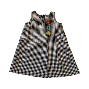 May include: A sleeveless black and white gingham dress with a zipper closure and three colorful flower appliqués. The dress has a pleated design and is suitable for children.