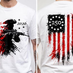 以下が含まれることがあります： 白いTシャツ。ライフルを持った兵士のグラフィック、数字の「1776」と「2026」、星が描かれています。Tシャツの背面には、番号「250」が付いた、使い古されたアメリカ国旗のデザインが表示されています。