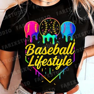 May include: Black t-shirt with a colorful graphic design. The design features three baseballs with dripping paint effects in pink, yellow, and blue. The text "Baseball Lifestyle" is written in a vibrant font.