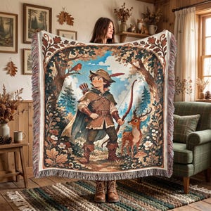 May include: A woven throw blanket featuring a central illustration of a forest archer wearing a green tunic, cape, and feathered hat, holding a bow and arrow. The scene includes a deer, a robin, and oak leaf borders with fringed edges.