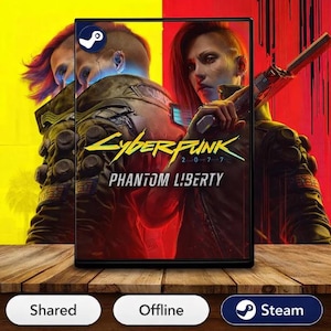 May include: A video game box for Cyberpunk 2077: Phantom Liberty. The cover art features a woman holding a gun, with a futuristic cityscape backdrop. The Steam logo is visible.