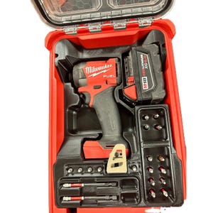 Pode incluir: Uma aparafusadora de impacto vermelha Milwaukee Fuel com uma bateria preta M18 Redlithium XC6.0, alojada numa mala de transporte de plástico vermelha com tampa transparente. A mala inclui compartimentos moldados com várias pontas de metal.