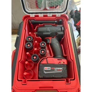 Può includere: Una valigetta portautensili rossa Milwaukee Packout contenente un avvitatore a impulsi nero M18 Fuel con batteria Redlithium XC 5.0. La valigetta include un interno sagomato con diverse bussole a impatto nere e una prolunga nera negli alloggiamenti.