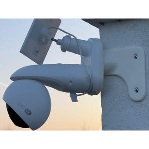 May include: A white security camera with a spherical lens housing labelled 4K, mounted to a wall bracket. A small white solar panel is attached to the top of the camera arm via an adjustable mount, connected by a thin white power cable.