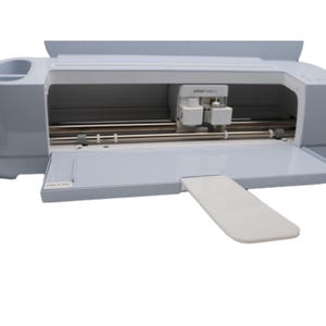 Puede incluir: Una máquina de corte electrónica Cricut Maker 3 de color azul claro con una carcasa de carro blanca, varillas metálicas horizontales y una bandeja frontal abierta. La máquina cuenta con un brazo de soporte blanco extensible y una etiqueta Maker 3 11830.