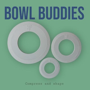 Può includere: Tre oggetti circolari bianchi con un foro al centro, disposti su uno sfondo verde. Il testo "BOWL BUDDIES" è in alto e "Compress and shape" in basso. Ogni oggetto ha una superficie strutturata.