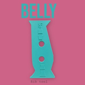 May include: A turquoise rib tool with the word "BELLY" above it and "Rib tool" below it, set against a pink background. The tool has a unique shape with two circular cutouts and several rectangular and square features.