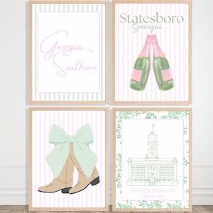 May include: Four framed prints with a light wood finish. The prints feature watercolor illustrations of Georgia Southern University themes. One print has the words "Georgia Southern" in pink script. Another shows two champagne bottles. A third shows cowboy boots with a bow. The last shows a building.