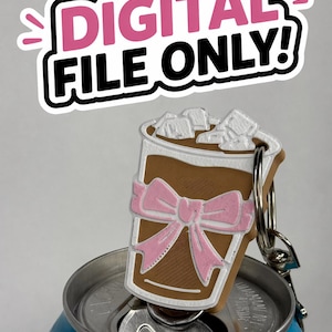 Op de afbeelding: Een bruin-witte sleutelhanger in de vorm van een ijskoffie, met een roze strik. De sleutelhanger is bevestigd aan een zilveren ring en rust op een blauw blikje. De tekst "DIGITAL FILE ONLY!" staat erboven.