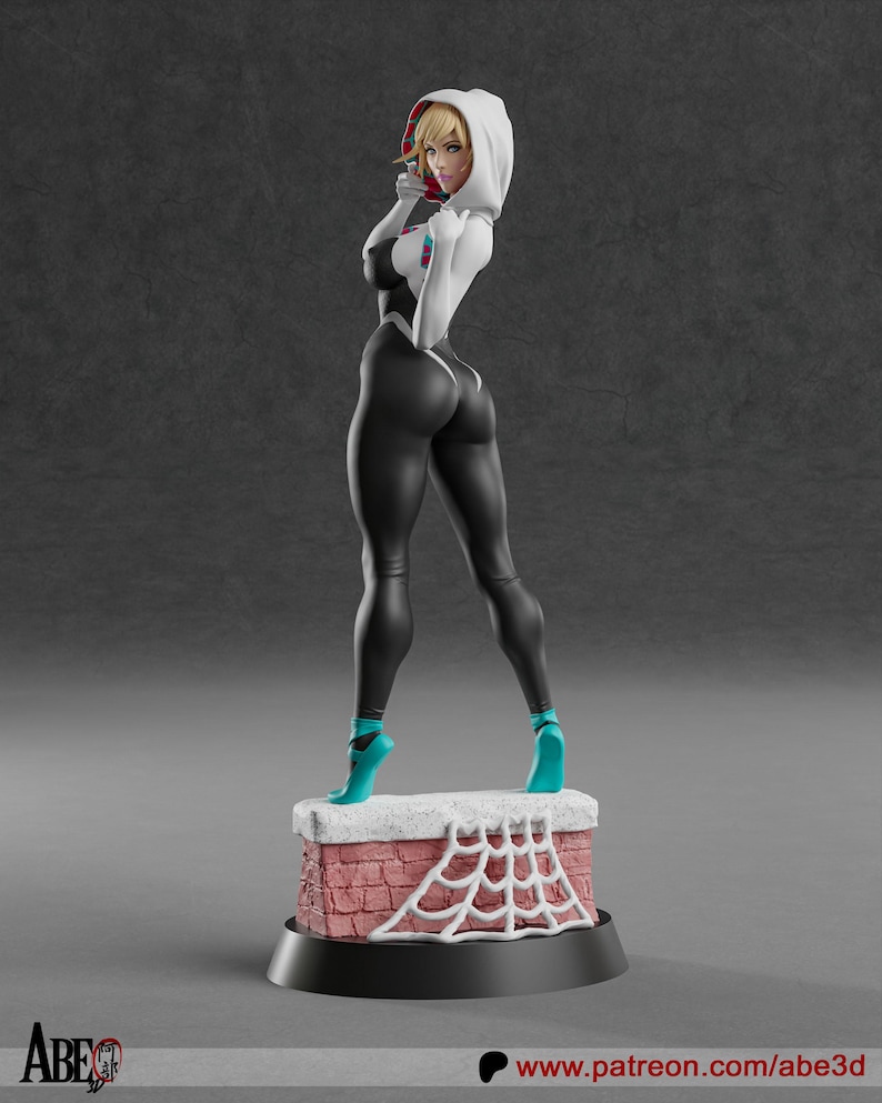 May include: A figurine of a female superhero in a black and white suit with a hood. The figure is standing on a brick chimney with a white spiderweb design. The figure is wearing teal shoes.