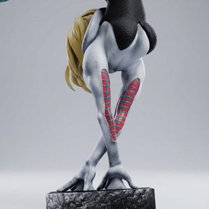 May include: A detailed figurine of a superheroine in a dynamic pose. The figure is predominantly white with black accents and red and teal details. The blonde hair contrasts with the dark suit. The figure is on a textured base.