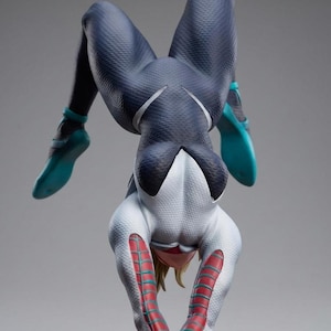 May include: A figurine of a character in a dynamic pose, wearing a white and navy blue suit with teal accents. The figure is upside down, showcasing the intricate design and textures of the costume.