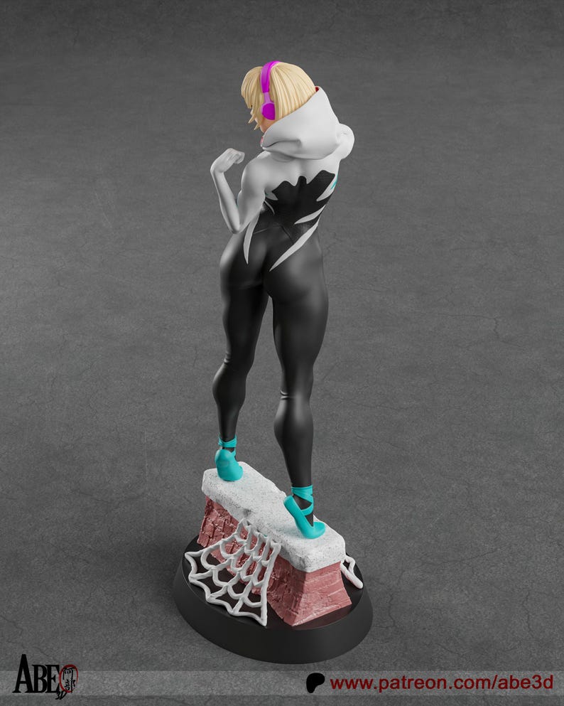 May include: A figurine of a female character in a black and white bodysuit, teal heels, and a white hooded jacket. The figure has blonde hair and pink headphones. The base features a brick-like structure with a white spiderweb design.