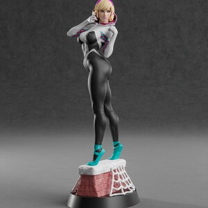 May include: A 3D-printed figurine of a female superhero in a black and white bodysuit with a spiderweb design. The figure has blonde hair and is wearing teal high heels. The figurine is standing on a red brick chimney with a white web design.