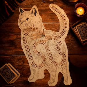 Peut inclure: Un plateau de jeu de cribbage en bois clair en forme de chat, présentant des détails de fourrure gravés et un chemin sinueux de trous percés pour le jeu. Le plateau inclut le mot finish près de la queue et possède une finition en bois naturel.