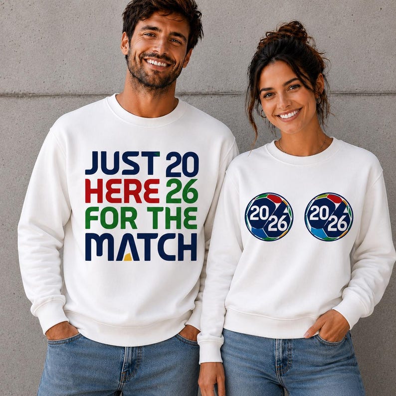 Puede incluir: Dos personas con sudaderas blancas. Una tiene el texto "JUST 20 HERE 26 FOR THE MATCH" en varios colores. La otra tiene dos gr&aacute;ficos de bal&oacute;n de f&uacute;tbol con "20/26" en su interior. Ambas son para un partido.