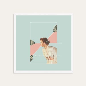 May include: A square framed art print featuring a collage of a person in a light-colored blouse positioned within a rectangular border. Three vintage cameras are directed toward the person, with pink triangular shapes and white dotted lines.