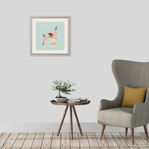 May include: A framed square wall art print featuring a collage of a person in a light-colored outfit against a pale blue background with pink geometric shapes, displayed above a small wooden side table with a bonsai tree and a gray wingback chair.