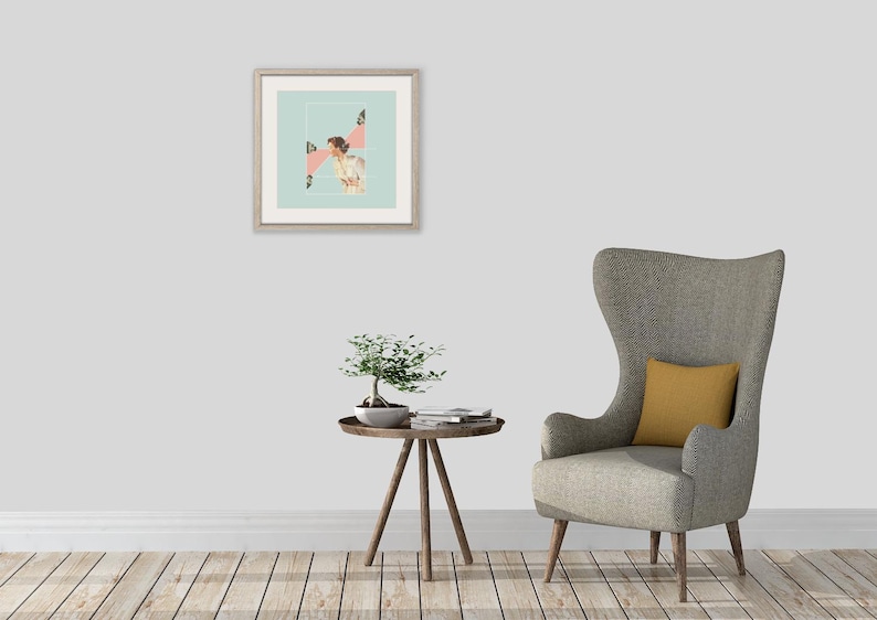 May include: A framed square wall art print featuring a collage of a person in a light-colored outfit against a pale blue background with pink geometric shapes, displayed above a small wooden side table with a bonsai tree and a gray wingback chair.