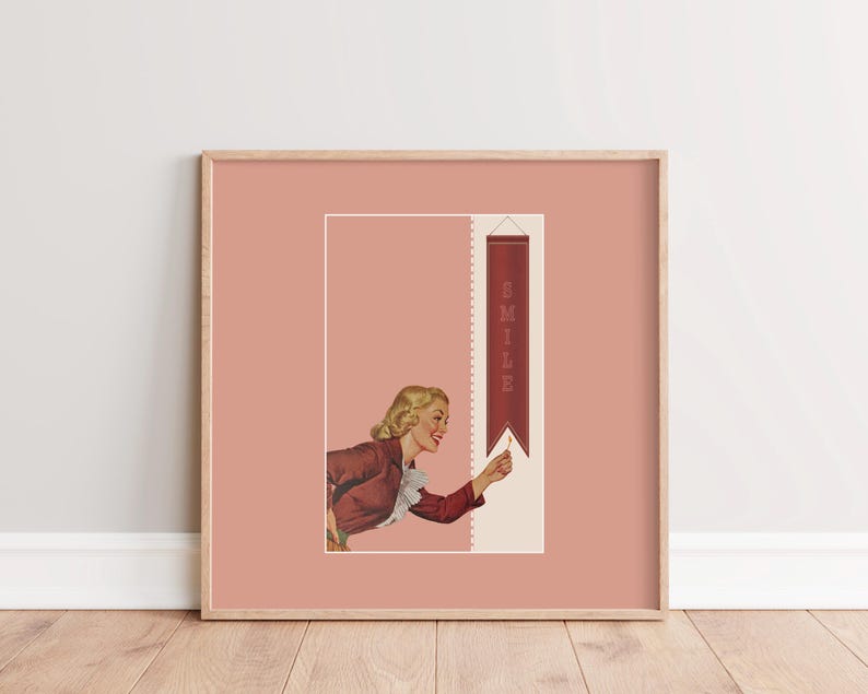 May include: A square framed wall art print featuring a dusty rose background. The illustration depicts a blonde person in a maroon jacket with a white ruffled collar, reaching toward a vertical maroon banner that displays the word SMILE in white.