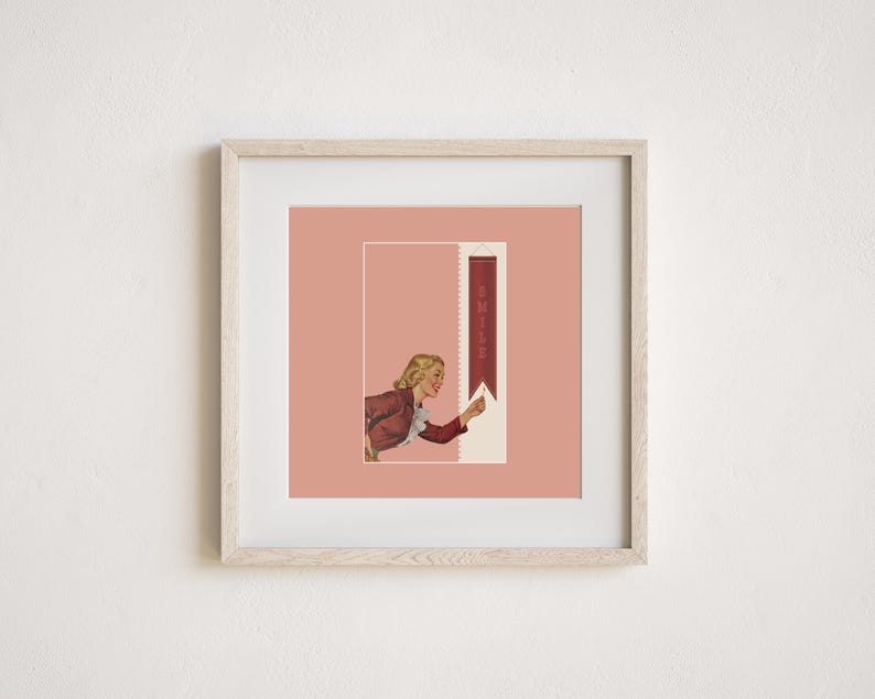 May include: A framed square print featuring a light pink background with a central illustration of a blonde person in a red jacket pointing toward a vertical dark red banner that contains the word SMILE in light-colored capital letters.