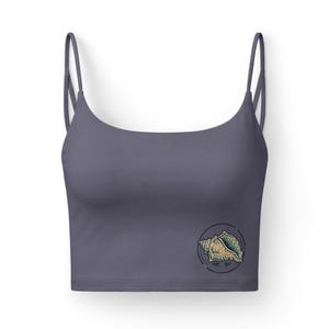 Könnte beinhalten: Ein schiefergraues Crop-Top mit dünnen Trägern. Auf der unteren rechten Seite ist eine runde Grafik einer Muschel in Beige-, Grün- und Blautönen aufgedruckt. Das Oberteil ist aus glattem, einfarbigem Stoff gefertigt.