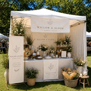 Może przedstawiać: Biały namiot typu pop-up dla Willow & Bloom Floral Studio z kremowymi banerami z nazwą i logo marki. Stoisko zawiera stół przykryty lnianym obrusem, kompozycje kwiatowe w wazonach oraz wiklinowe kosze.