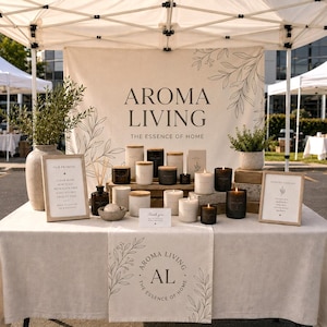 Op de afbeelding: Een kraam op een openluchtmarkt met Aroma Living geurkaarsen en diffusers. De kaarsen, in verschillende maten en kleuren, hebben houten deksels. De tafel is bedekt met een neutraal gekleurde doek, en de achtergrond toont het logo en de slogan van het merk.