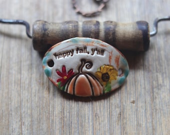 Handmade ceramic pottery pendant featuring the playful phrase "Happy Fall Y'all," perfect for adding a cozy autumn touch to any outfit.