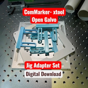 May include: A light blue plastic jig adapter set featuring multiple slotted components arranged on a square white base plate. The set is designed for use with ComMarker and xtool Open Galvo laser systems. A digital download product for laser engraving.