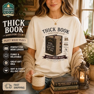 Puede incluir: Camiseta color crema con el texto "THICK BOOK SURVIVOR CLUB" y un gráfico de un libro. La camiseta también presenta el texto "PLOT? WHAT PLOT?" y términos relacionados con libros. Una persona lleva la camiseta y sostiene una taza.
